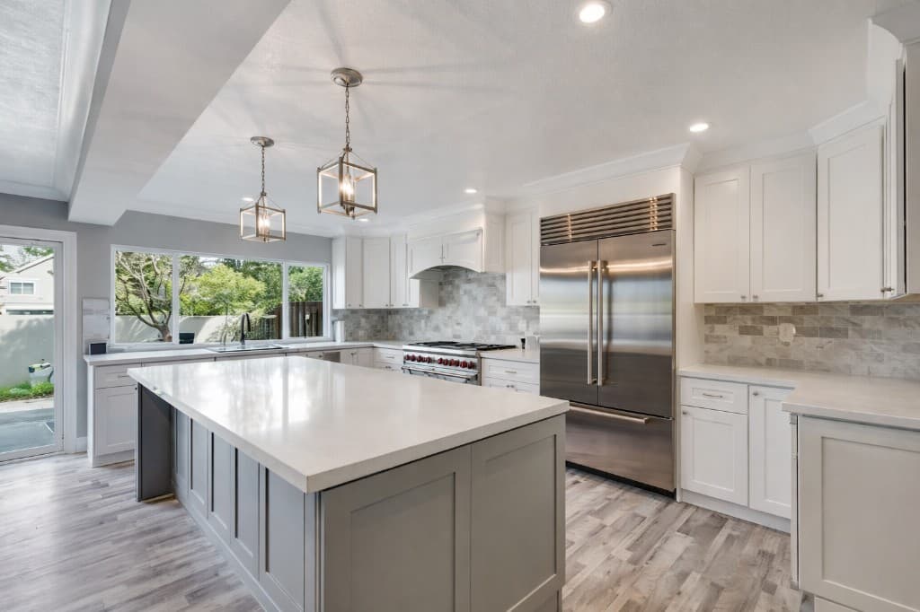 White kitchen with a grey island and pendant lighting